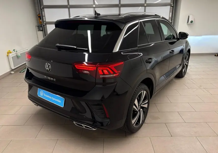 Vue 3/4 arrière droite d'un Volkswagen T-Roc noir intense avec feux arrière LED et jantes alliage distinctives.