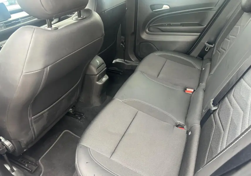 Vue intérieure arrière côté droit du Jeep Avenger 2025, sièges tissu et cuir noirs avec ceinture de sécurité visible.