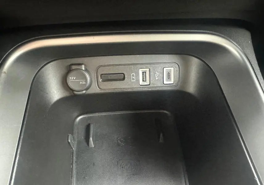 Vue rapprochée de la console centrale du Jeep Avenger 2025, montrant prises USB, prise 12V et zone de recharge sans fil noire.