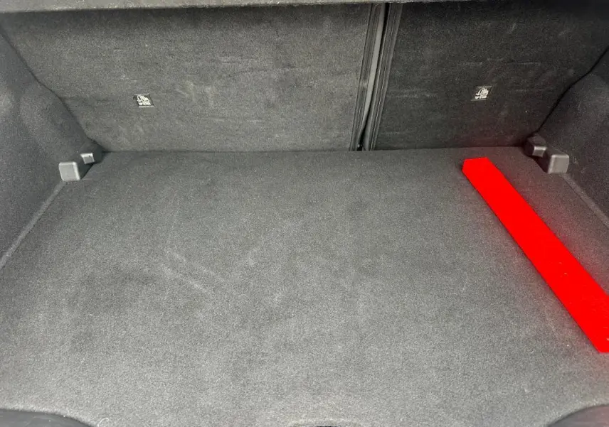 Coffre spacieux et propre du Jeep Avenger gris foncé, avec tapis de sol et rangement visible en angle droit.