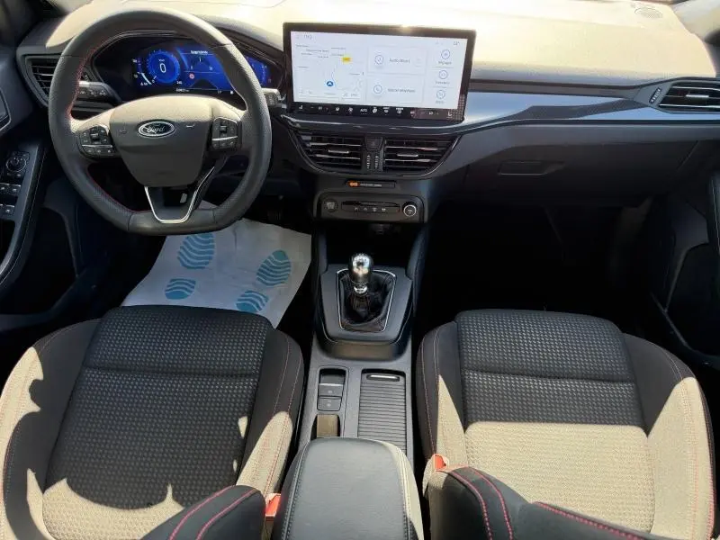 Vue intérieure avant de la Ford Focus SW 2023, tableau de bord moderne avec écran tactile et volant multifonction noir.