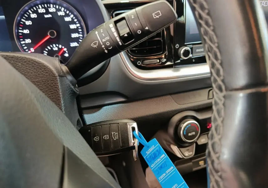 Gros plan sur le volant et tableau de bord du Kia Stonic gris foncé, avec clé de contact et commandes visibles.