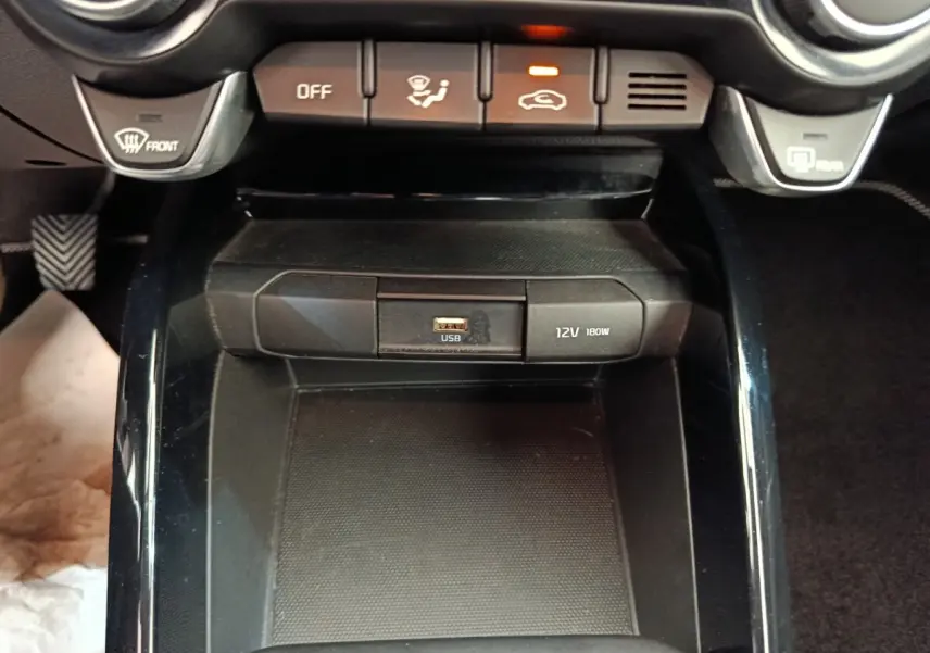 Vue rapprochée du compartiment central noir avec prise USB et port 12V dans l’habitacle d’une KIA Stonic 2023.