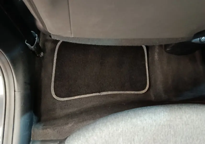 Vue rapprochée du tapis de sol arrière noir avec bordure claire dans une KIA Stonic gris foncé 2023.
