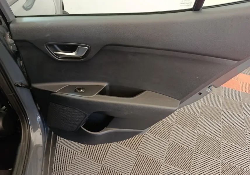Vue intérieure de la porte arrière gauche du KIA STONIC gris foncé, avec poignée et commande de vitre électrique.