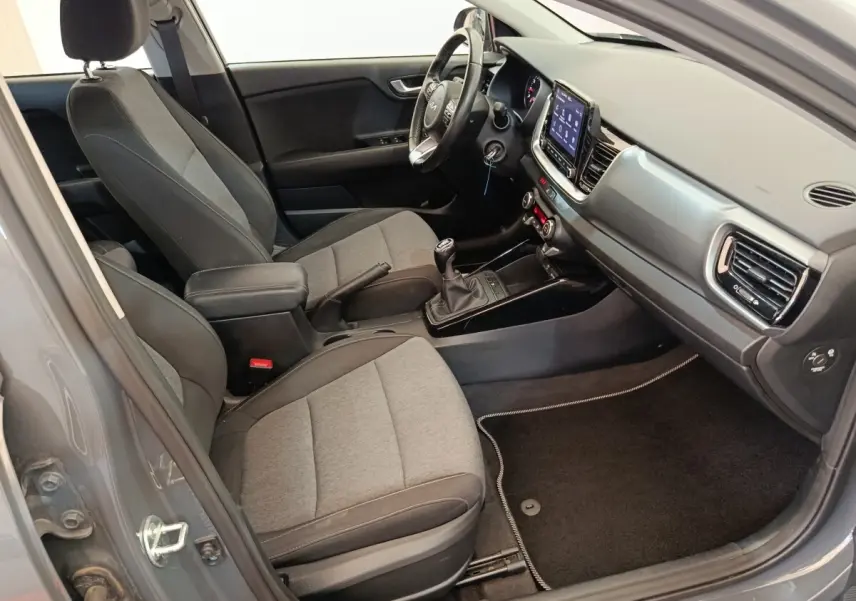 Vue intérieure côté conducteur de la KIA Stonic gris foncé 2023, avec tableau de bord moderne et écran tactile central.