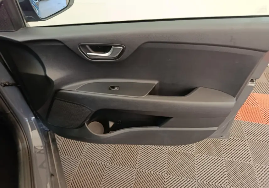 Vue intérieure de la porte avant gauche gris foncé du KIA STONIC 2023 avec poignée et commande de fenêtre simple.