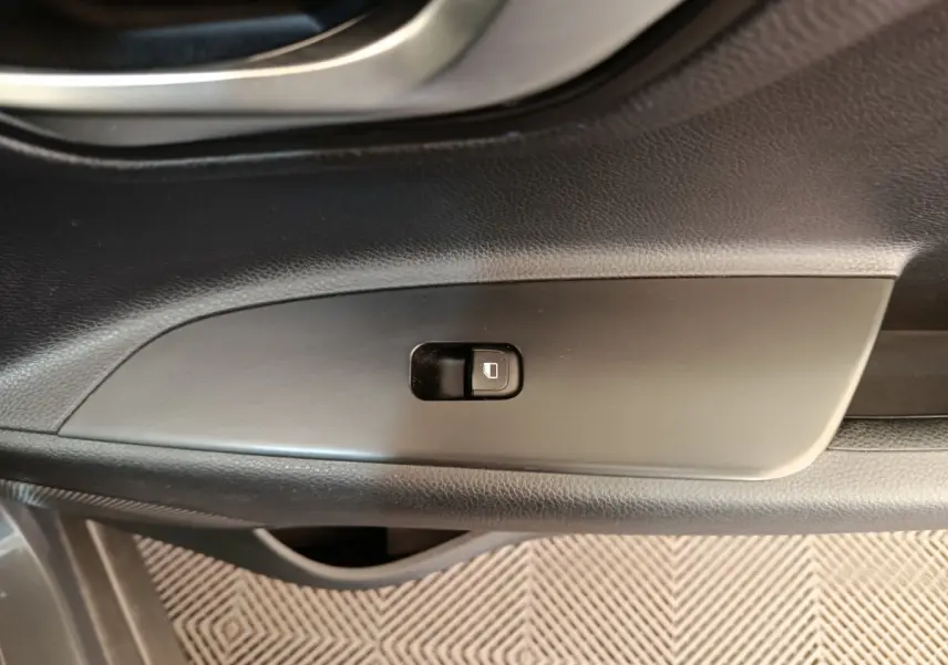 Gros plan sur le bouton de verrouillage des portes côté conducteur dans l'intérieur gris foncé de la KIA Stonic 2023.
