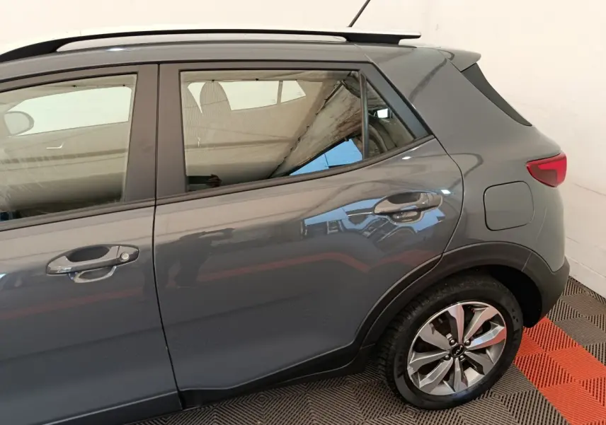 Vue latérale droite d'un KIA Stonic gris foncé montrant la porte arrière, la roue et la lunette arrière.