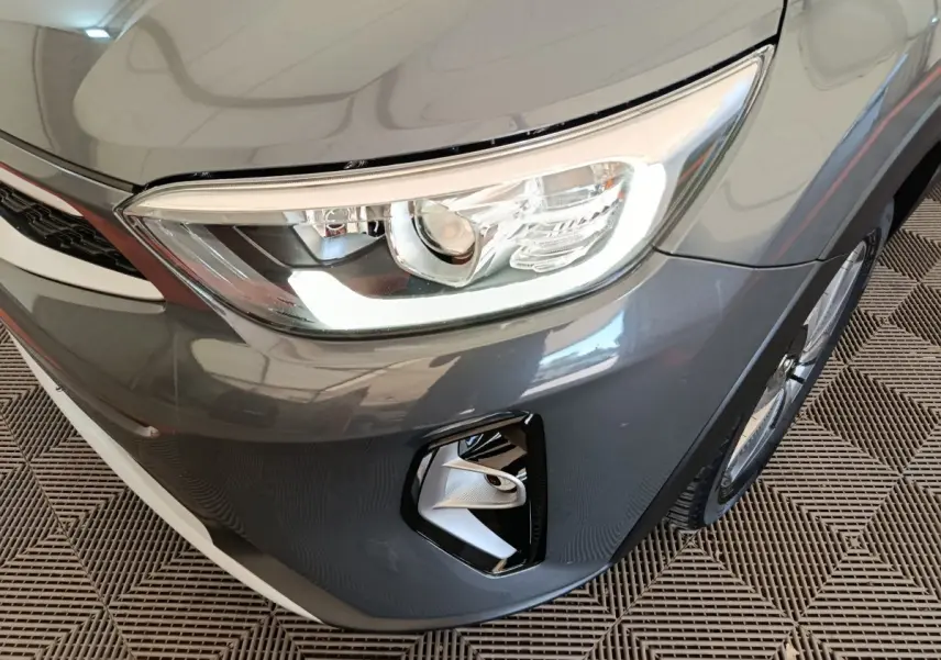 Gros plan sur l'avant droit gris foncé du KIA Stonic 2023, mettant en valeur le phare et le feu antibrouillard.