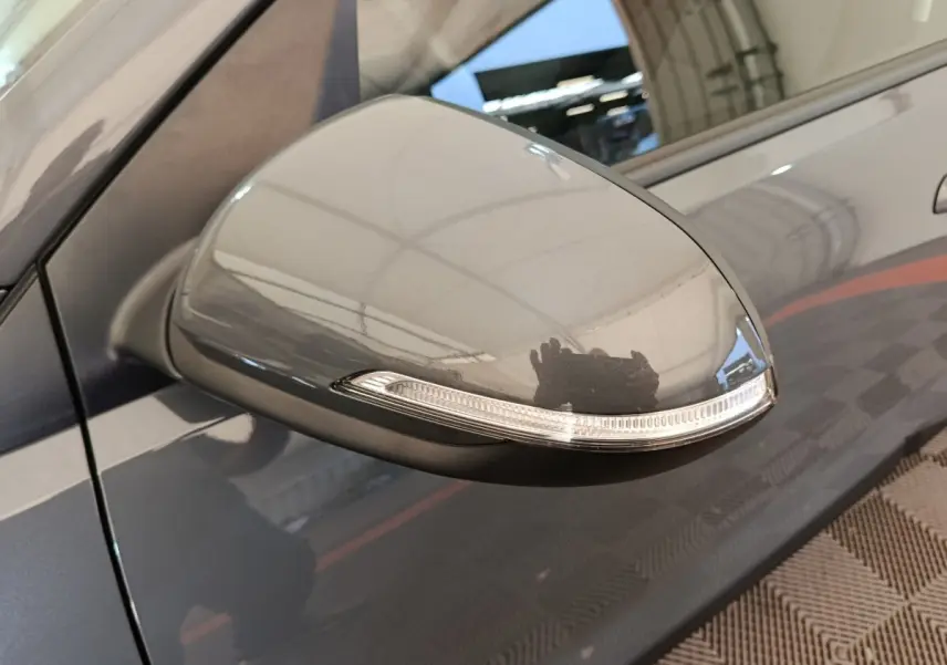 Rétroviseur côté gauche gris foncé de la KIA Stonic 2023 avec clignotant intégré, vue rapprochée en extérieur.