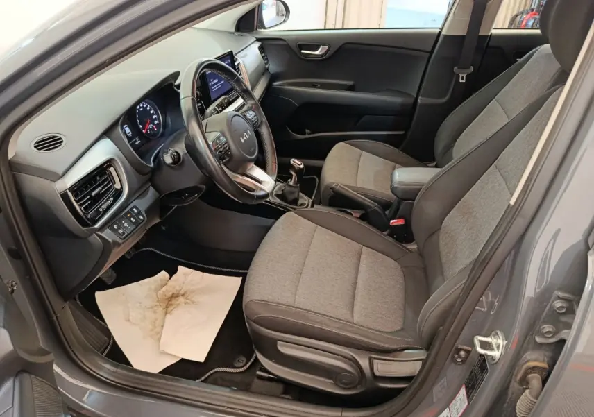 Vue intérieure côté conducteur de la KIA Stonic gris foncé 2023 avec sièges tissu bicolore et volant cuir multifonctions.