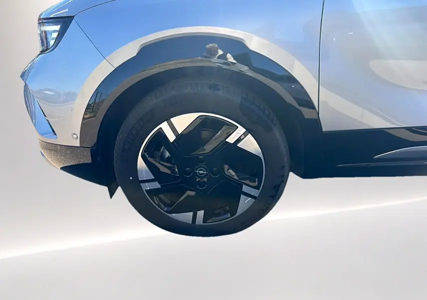 Gros plan sur la roue avant gauche et une partie de la carrosserie gris clair de l'Opel Mokka Electric 2025.