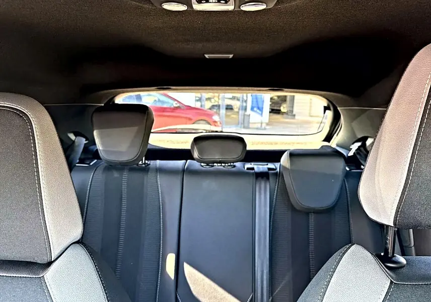 Vue intérieure arrière de l'Opel Mokka Electric 156 GS 2025, sièges gris foncé avec appuie-têtes et ceintures visibles.