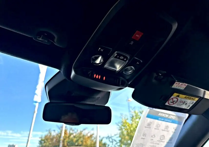 Vue intérieure du toit et rétroviseur d’un Opel Mokka Electric gris, avec commandes d’éclairage et bouton SOS visibles.