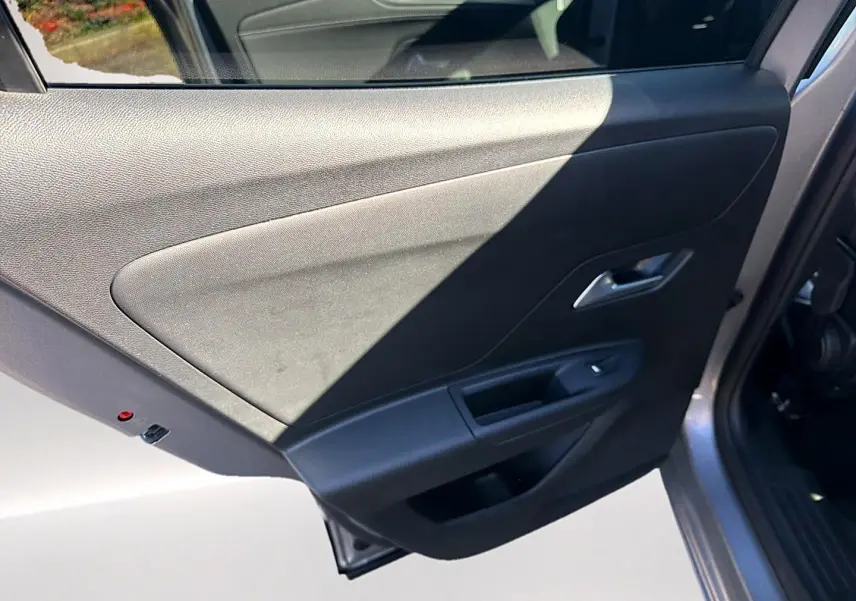 Vue rapprochée de la porte arrière droite grise de l’Opel Mokka Electric 156 gs avec poignée et commande de vitre.