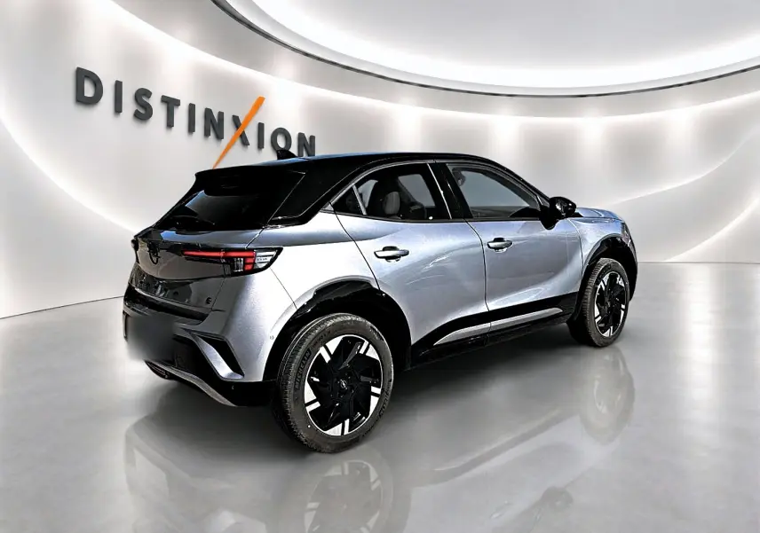 Opel Mokka Electric 156 GS gris 3/4 arrière droit avec toit noir et jantes alu bicolores dans showroom.