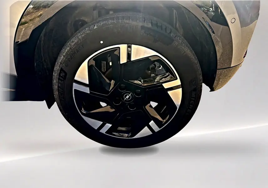 Gros plan sur la roue avant droite avec jante alu noire et grise de l'Opel Mokka Electric gris 2025.