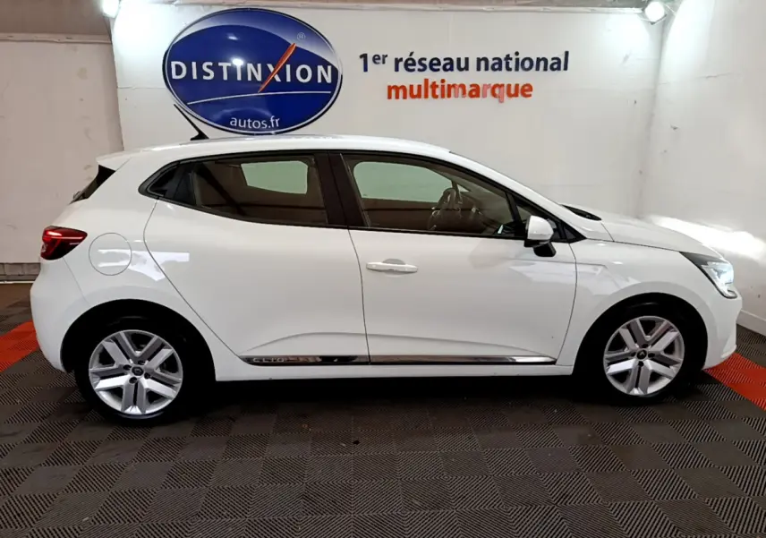 Profil côté gauche d'une Renault Clio Business Blue dCi 85 blanche, vue en intérieur avec jantes alliage et rétroviseurs blancs.