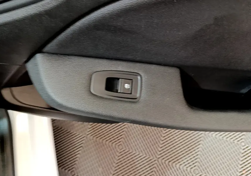 Bouton de commande de lève-vitre sur la porte intérieure côté conducteur d'une Renault Clio Business Blue dCi 85 blanche.