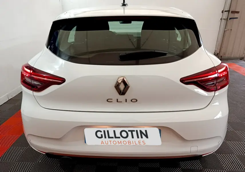 Vue arrière d'une Renault Clio blanche 2020 avec feux LED et logo Renault bien visibles dans un garage.