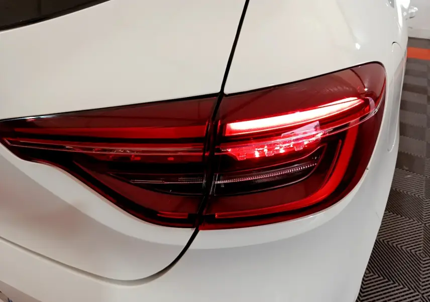 Gros plan sur le feu arrière droit rouge d'une Renault Clio Business Blue dCi 85 blanche, vue arrière détaillée.