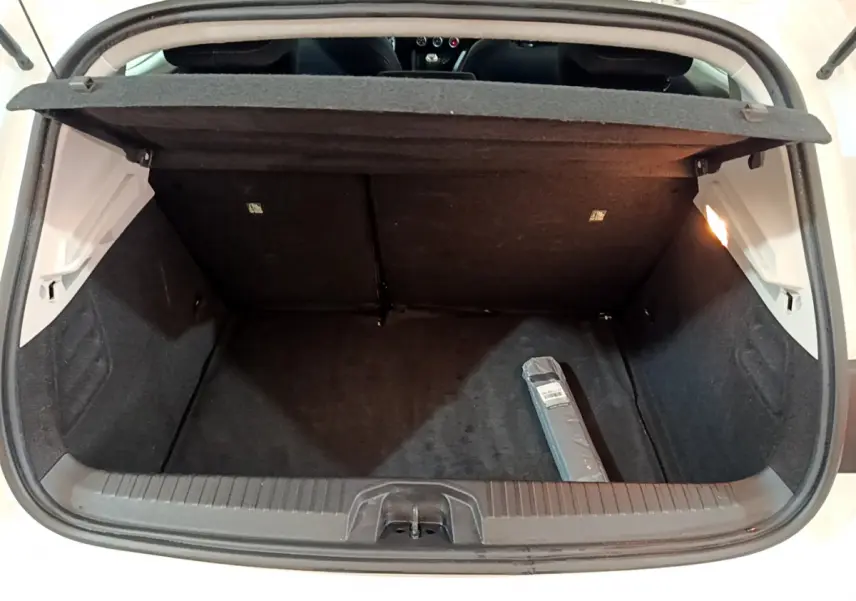 Coffre ouvert vu de l'arrière d'une Renault Clio Business Blue dCi 85 blanche, intérieur noir avec un objet emballé.