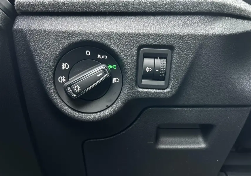 Gros plan sur le bouton de commande des phares du côté gauche intérieur du Skoda Kamiq gris graphite 2025.