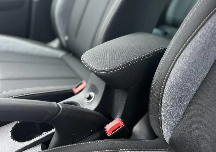 Détail de l'accoudoir central et des sièges avant gris foncé du Skoda Kamiq TSI 116 DSG7, intérieur moderne.
