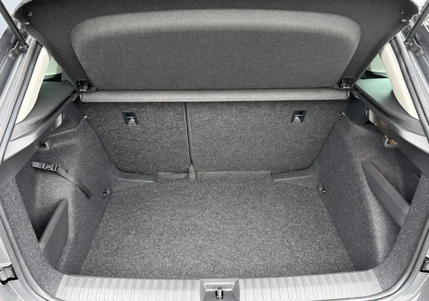 Coffre ouvert vu de l'arrière du Skoda Kamiq gris graphite, montrant un espace de chargement propre et spacieux.