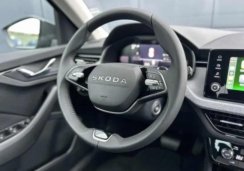 Vue intérieure centrée sur le volant noir multifonctions d’une Skoda Kamiq 2025 avec écran tactile et commandes au volant.