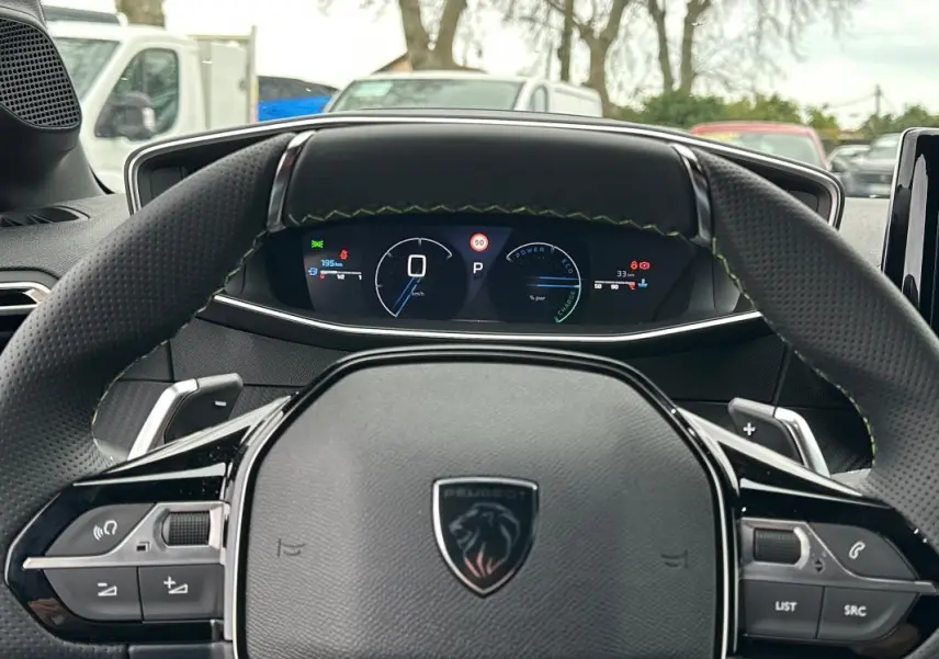 Vue intérieure centrée sur le volant Peugeot 208 gris, avec cockpit numérique et commandes intégrées visibles.