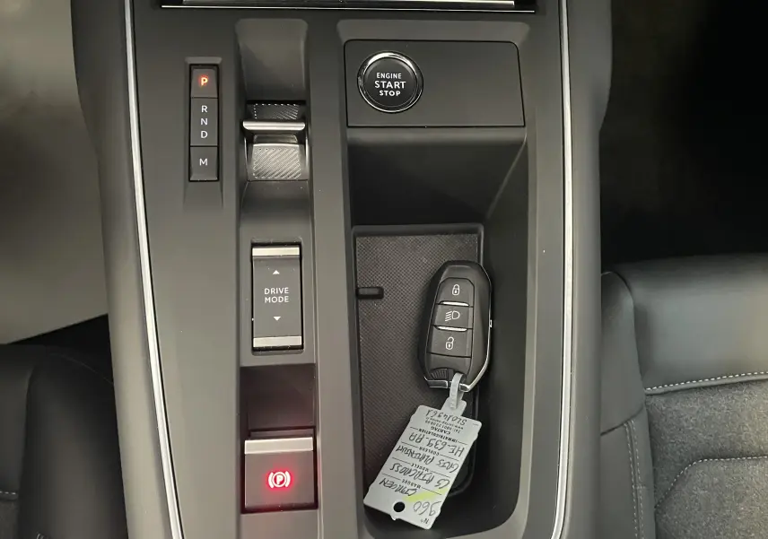 Vue en plongée sur la console centrale de la Citroën C5 Aircross hybride 2025, avec clé et bouton start/stop visibles.