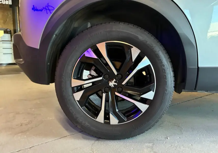 Gros plan sur la roue avant gauche du Peugeot 2008 gris 2022, mettant en valeur la jante alliage noire et argentée.