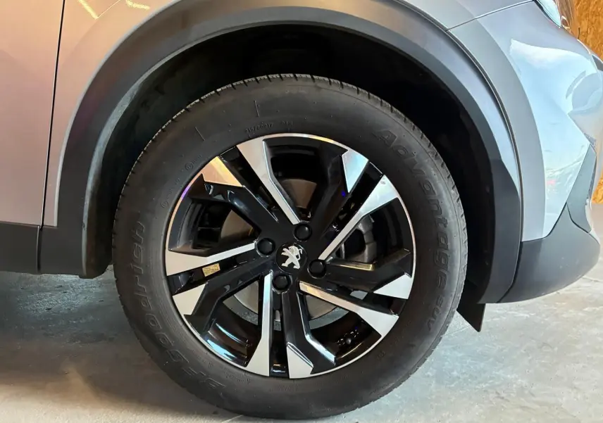 Gros plan sur la roue avant gauche du Peugeot 2008 gris 2022, mettant en valeur la jante alliage bicolore et le logo lion.