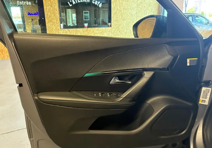 Vue intérieure de la porte avant gauche du Peugeot 2008 gris, avec garniture noire et insert effet carbone.