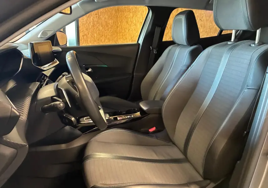 Vue intérieure côté conducteur du Peugeot 2008 2022, sièges en tissu noir et tableau de bord moderne avec écran tactile.
