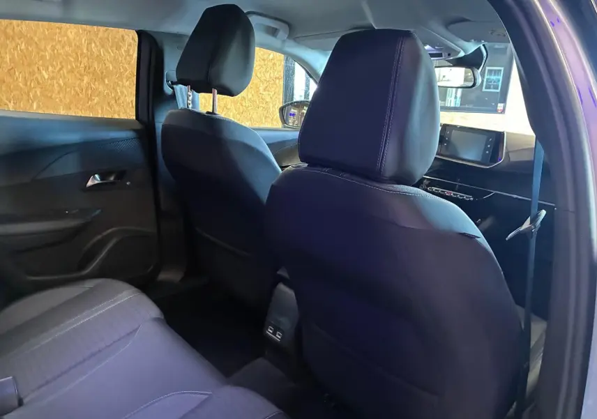 Vue intérieure arrière côté droit du Peugeot 2008 gris 2022, sièges noirs en tissu et tableau de bord avec écran tactile.