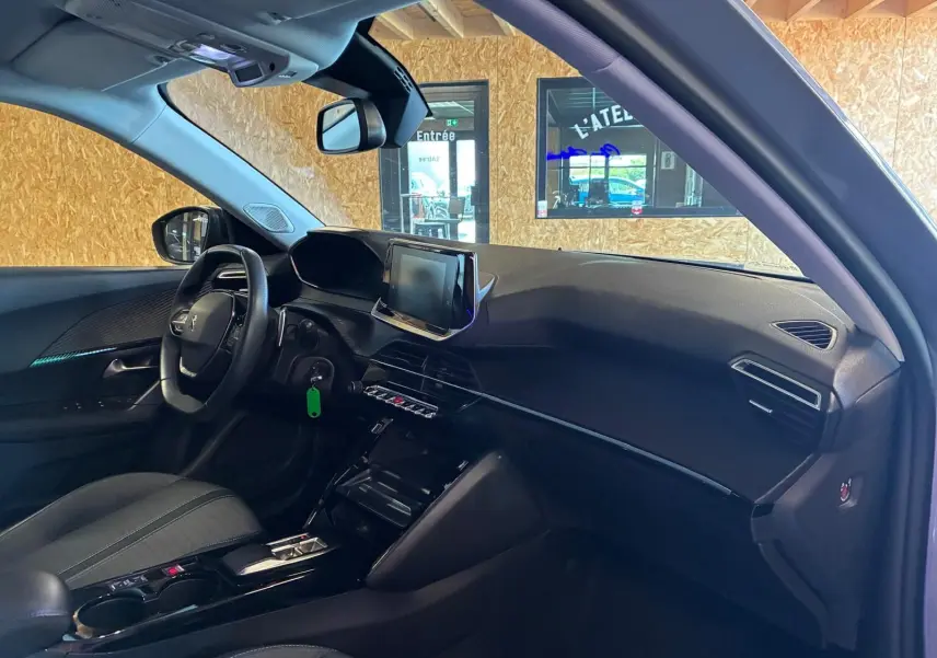 Vue intérieure côté conducteur du Peugeot 2008 gris 2022, mettant en valeur le tableau de bord et l’écran tactile central.