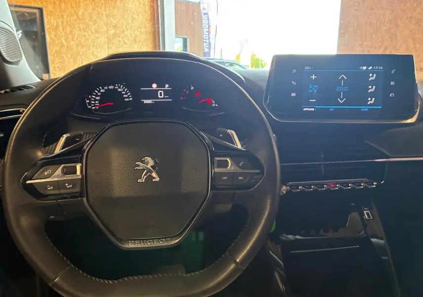 Vue intérieure centrée sur le volant noir du Peugeot 2008 2022 avec tableau de bord digital et écran tactile de climatisation.