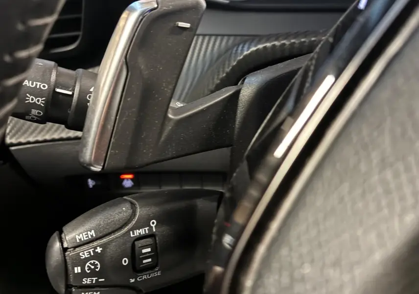 Gros plan sur la commande de régulateur de vitesse et palettes au volant du Peugeot 2008 gris, intérieur noir.