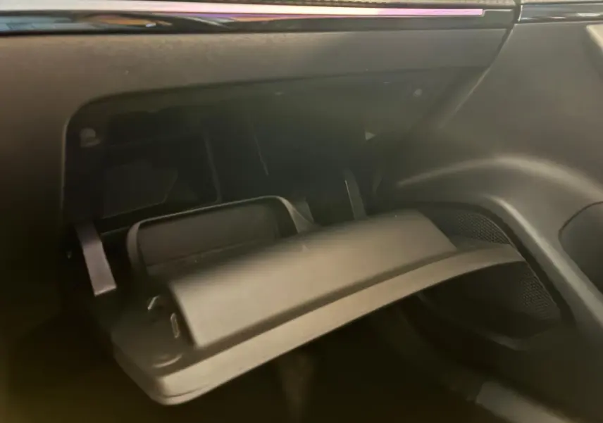 Gros plan sur la boîte à gants ouverte côté passager de la Peugeot 2008 gris 2022, intérieur noir.