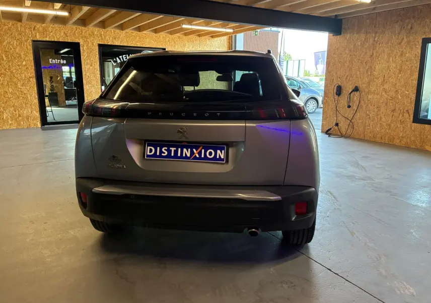 Vue arrière d’un Peugeot 2008 gris 2022 dans un garage, avec plaque d’immatriculation Distinxion visible.