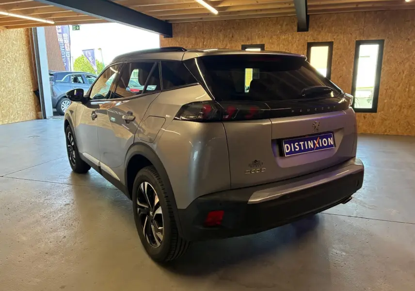 Peugeot 2008 gris en 3/4 arrière droit dans un garage, avec toit noir et feux arrière sombres distinctifs.