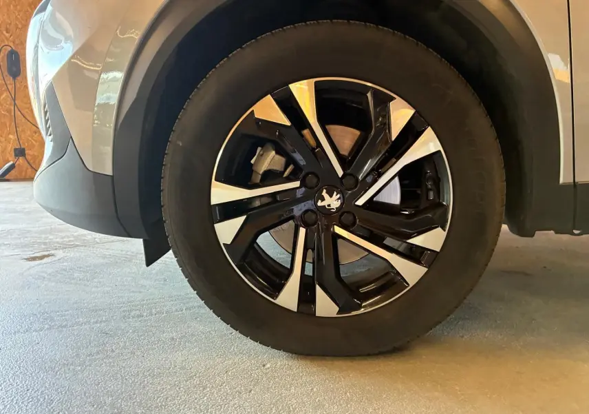 Gros plan sur la roue avant droite du Peugeot 2008 gris 2022, avec jante alliage noire et argentée au design moderne.