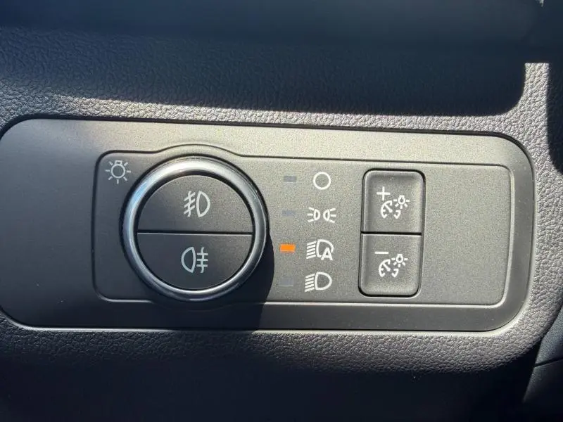 Gros plan sur les commandes d’éclairage du Ford Kuga 2024, avec molette et boutons noirs sur tableau de bord gris.