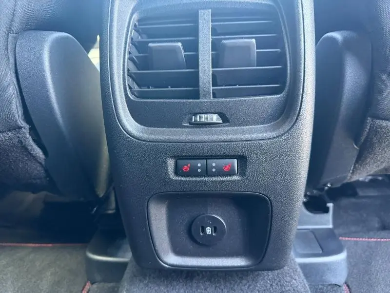 Vue rapprochée de la console arrière noire du Ford Kuga gris Solar avec commandes de sièges chauffants et prise 12V.