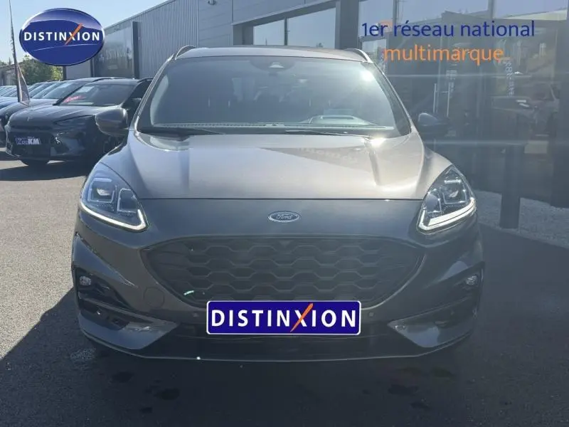 Vue frontale d'un Ford Kuga 2024 gris Solar métallisé avec calandre noire et feux LED allumés.