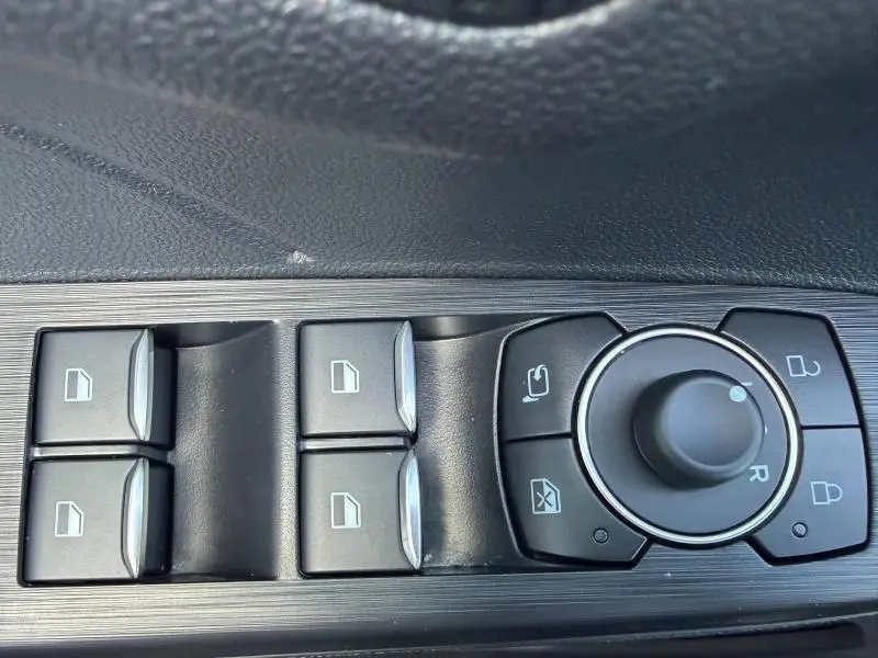 Gros plan sur les commandes des vitres et rétroviseurs côté conducteur du Ford Kuga gris Solar Métallisée 2024.