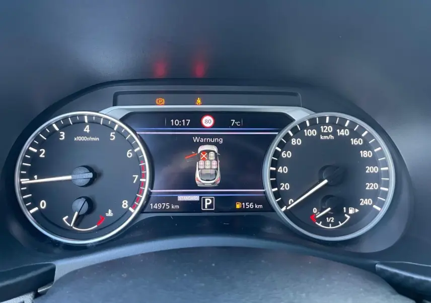 Vue rapprochée du combiné d'instruments digital du Nissan Juke II bleu Magnetic, affichant alertes et compteurs.